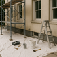 image of an outdoor building near a sidewalk, ground covered by canvas drop cloth and a scaffolding for painters near the buildings window.